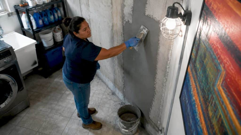 Homeowner applying waterproofing coating on basement wall