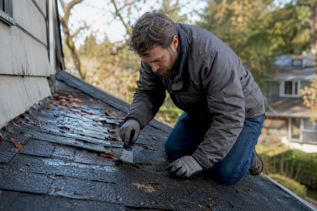 Person puncturing roof leak to drain water