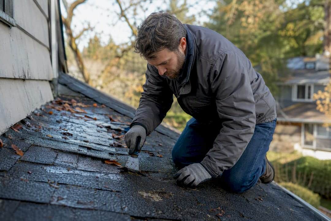 Person puncturing roof leak to drain water