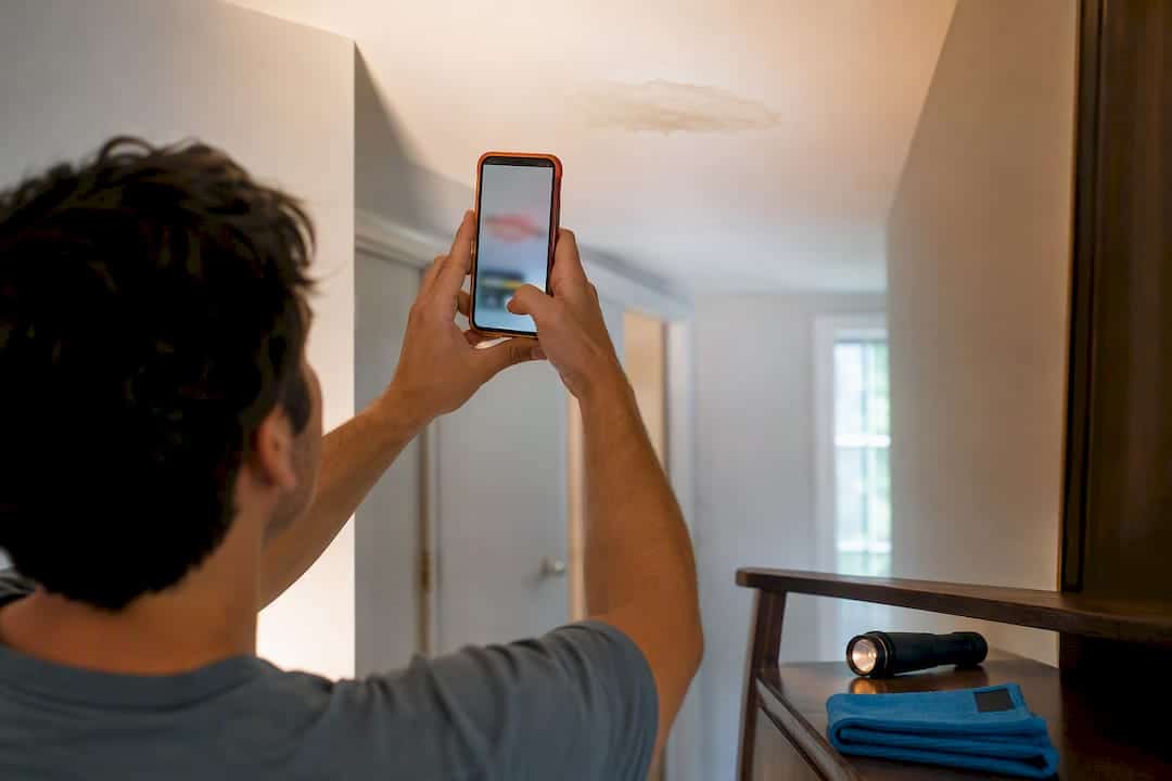 Homeowner photographing a ceiling water stain