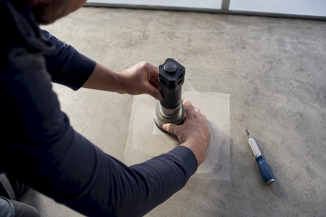 Technician testing primer adhesion on concrete