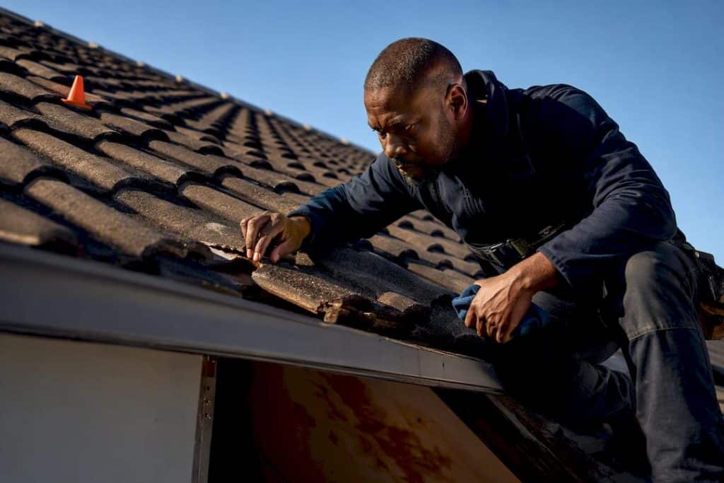 Professional inspecting a damaged roof tile