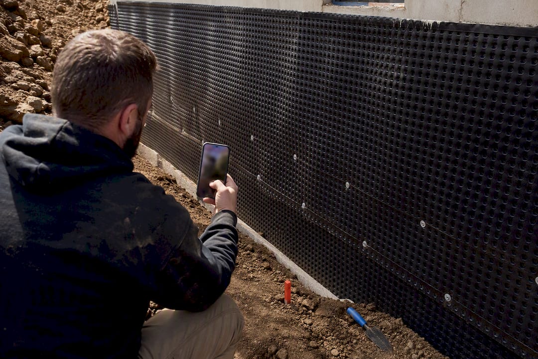 Technician documenting drainage board before backfill