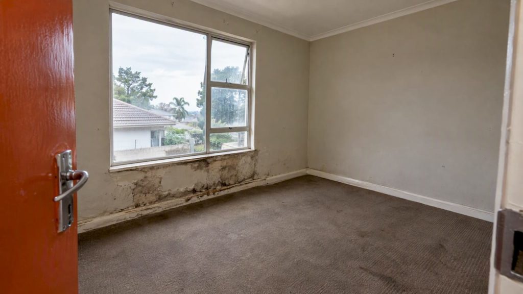 Damp damage around a rental bedroom window